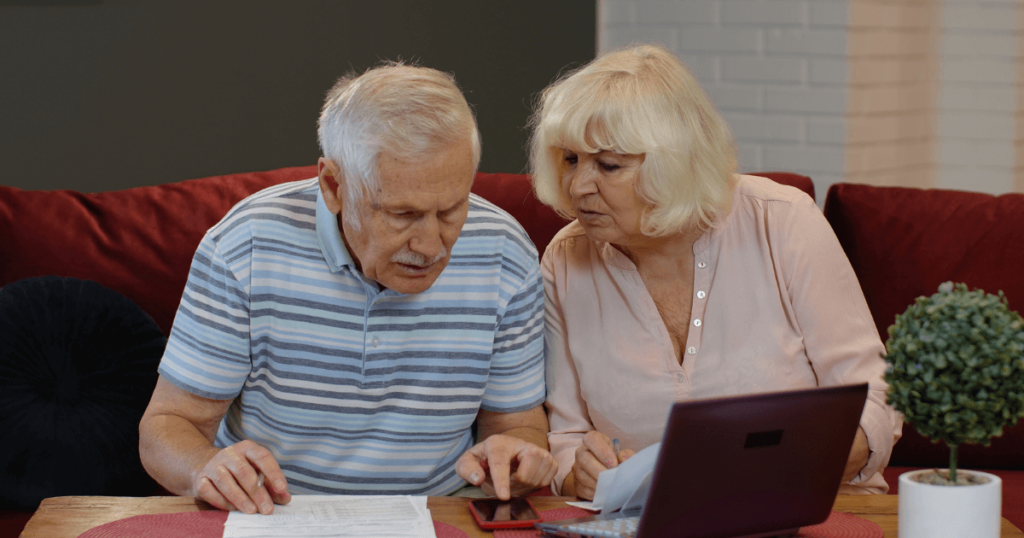 Senior couple researching on a computer comparing the cost of senior living versus staying at home.